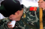 2008年2月3日，一名武警战士在京珠高速公路破冰铲雪间隙吃雪解渴。（来源：新华社） - 广播电视